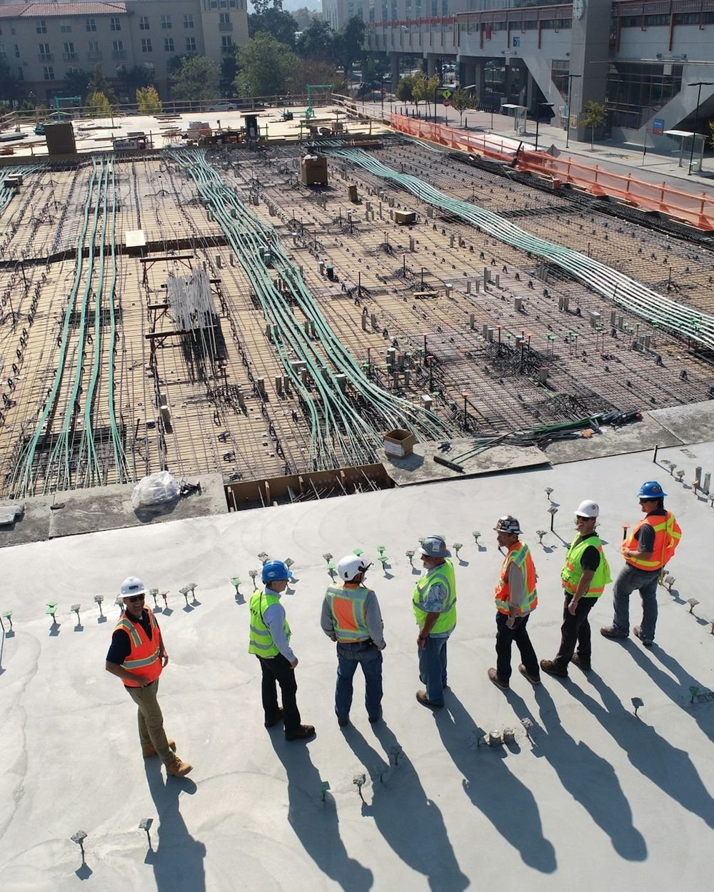 Diverse team of engineers and skilled workers in safety helmets reviewing plans at a construction site